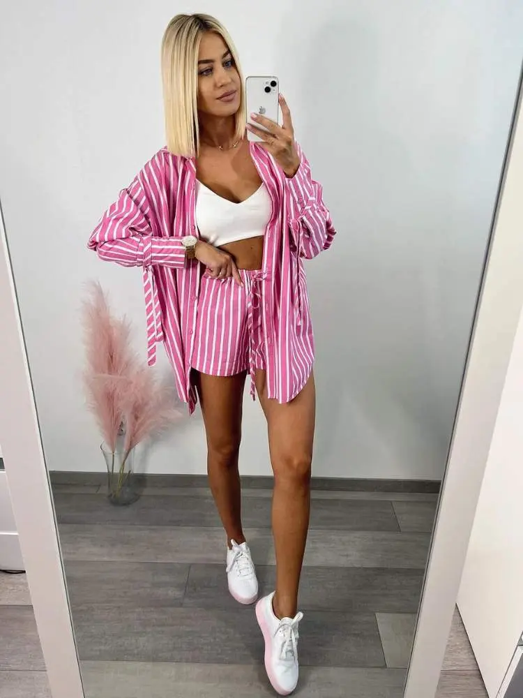 Mulher veste look listrado em rosa e branco como sugestão de roupa para ano novo na praia