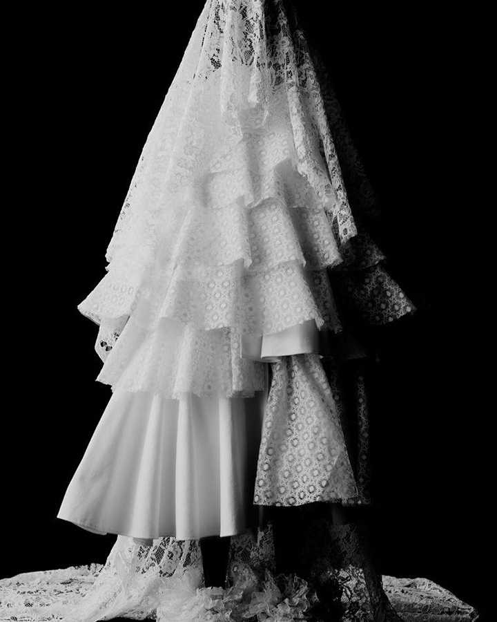 Vestido branco de renda com véu de renda. Foto em preto e branco.