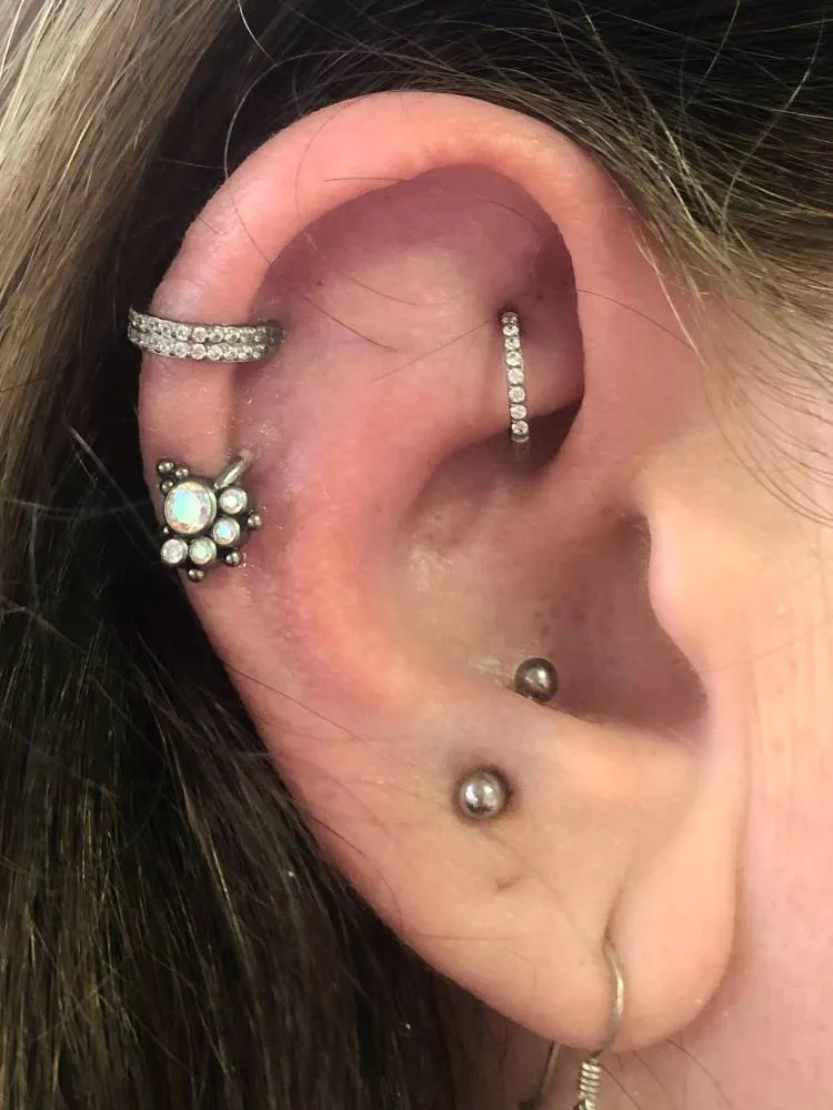 Orelha com piercing na hélix, rook e snug, tudo em prata.