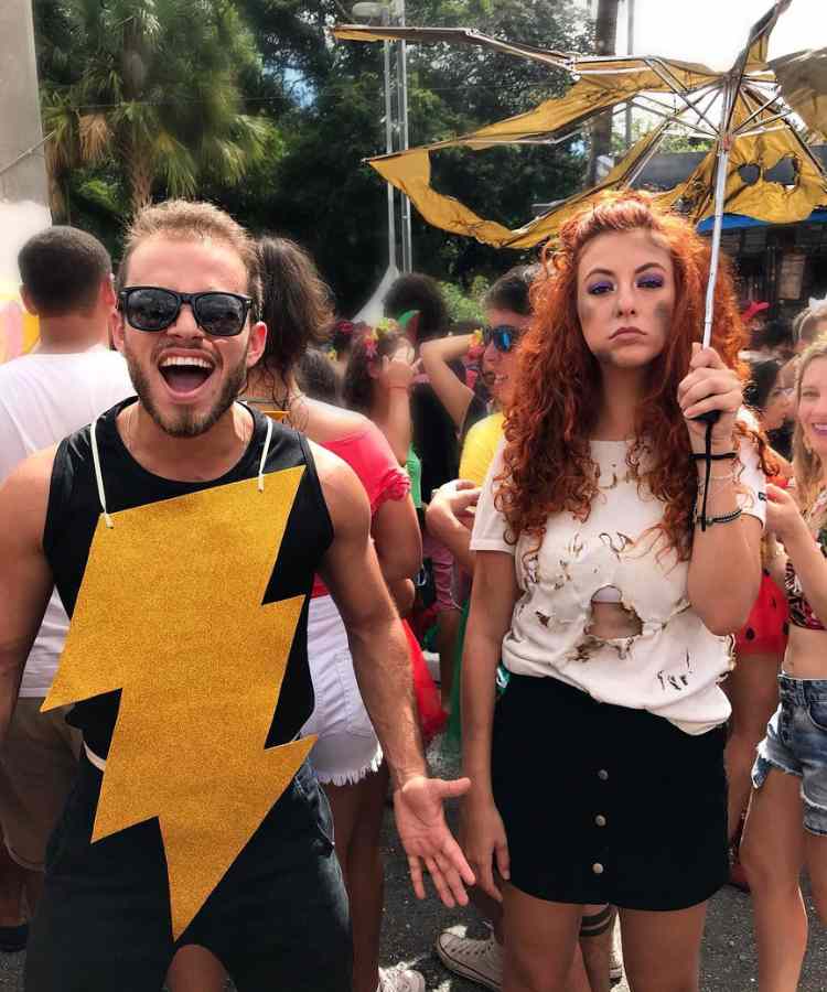 Traje de Dia das Bruxas para namorados: Casal tempestade. Ele usa roupa preta e desenho de raio dourado enquanto ela simula alguém "tostado", com maquiagem preta, roupa rasgada e guarda-chuva rasgado 