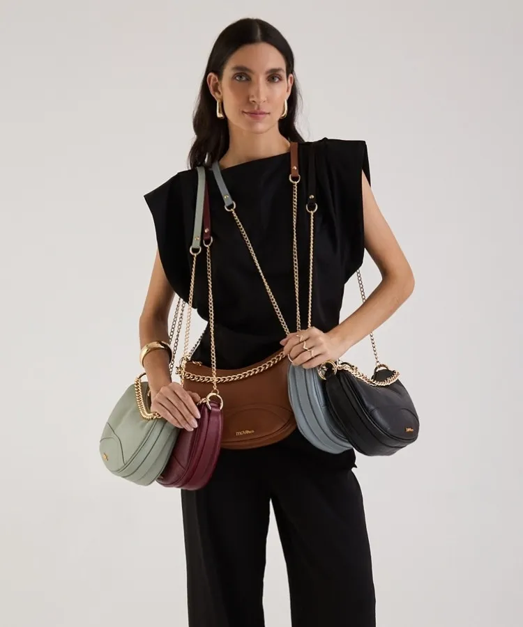 Modelo usando look preto e segurando bolsas de couro pequenas coloridas da Move & Co