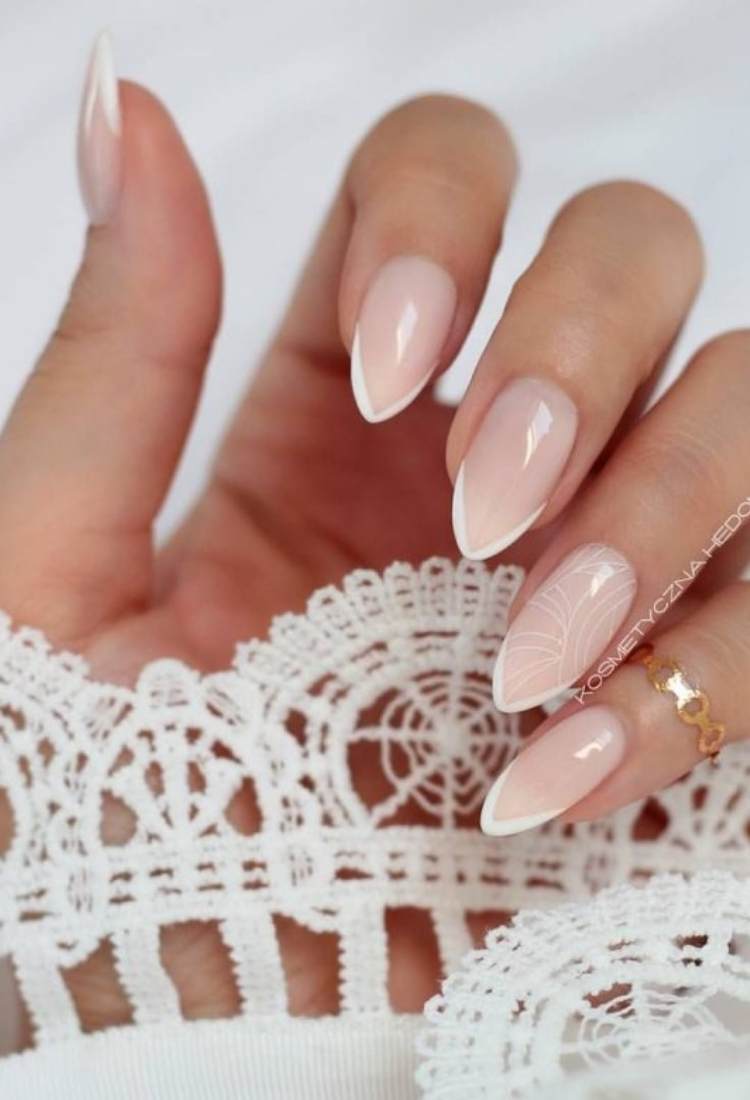 Unhas almond com francesinha e desenhos em branco no anelar