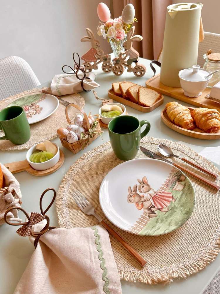 Mesa posta de Páscoa em tons de bege e verde, com pratos de coelho, sousplat bege, cestinha de ovos, coelhos de madeira e mais