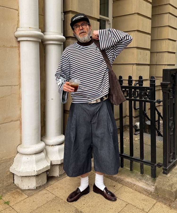 Homem usando camiseta listrada de manga comprida com modelagem oversized e bermuda