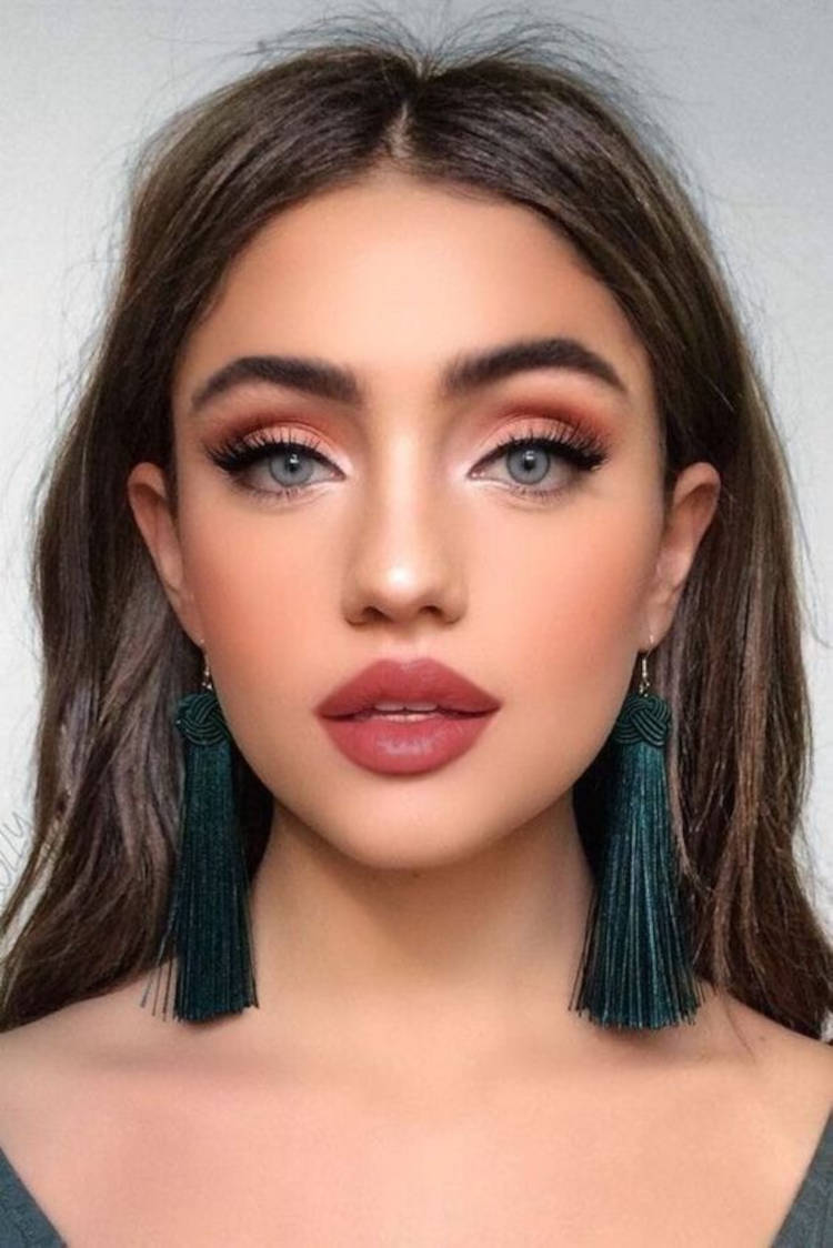 Mulher de pele clara com maquiagem esfumada e batom terroso 