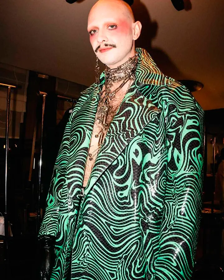 Modelo usando terno verde com padrão preto.
