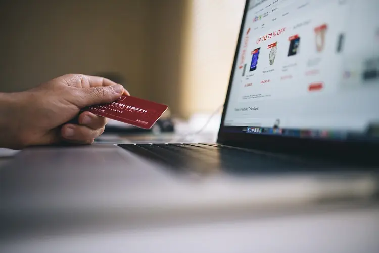 pessoa usando cartão de crédito em site de cupons de desconto