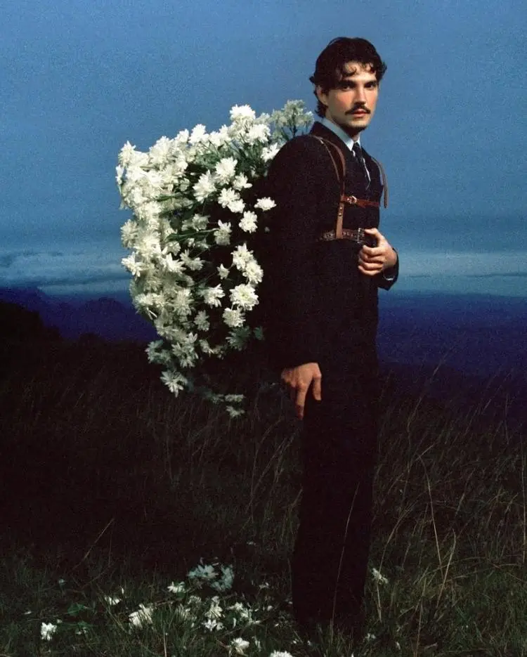 Em imagem de divulgação de Memórias Póstumas, Jão veste terno Gucci com asas de anjo feitas de flores brancas