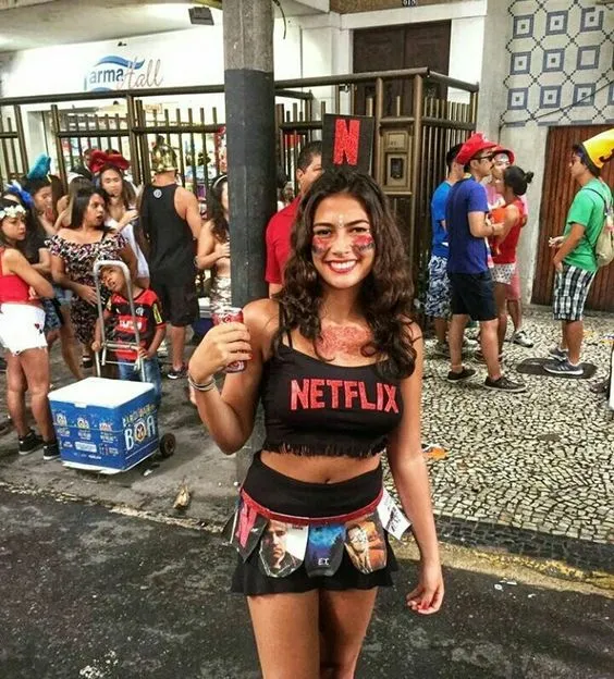 Mulher de pele clara com cropped preto escrito "netflix" e saia preta com filmes