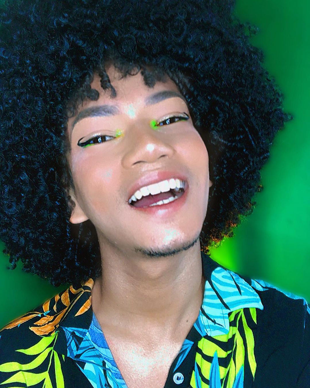 Homem de pele morena com delineado preto e ponto de luz neon verde