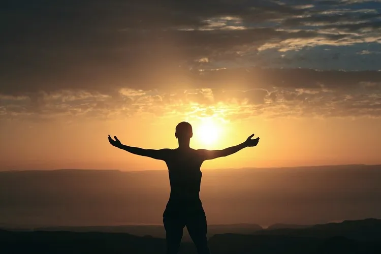 homem de braços abertos para o nascer do sol se conectando com a espiritualidade