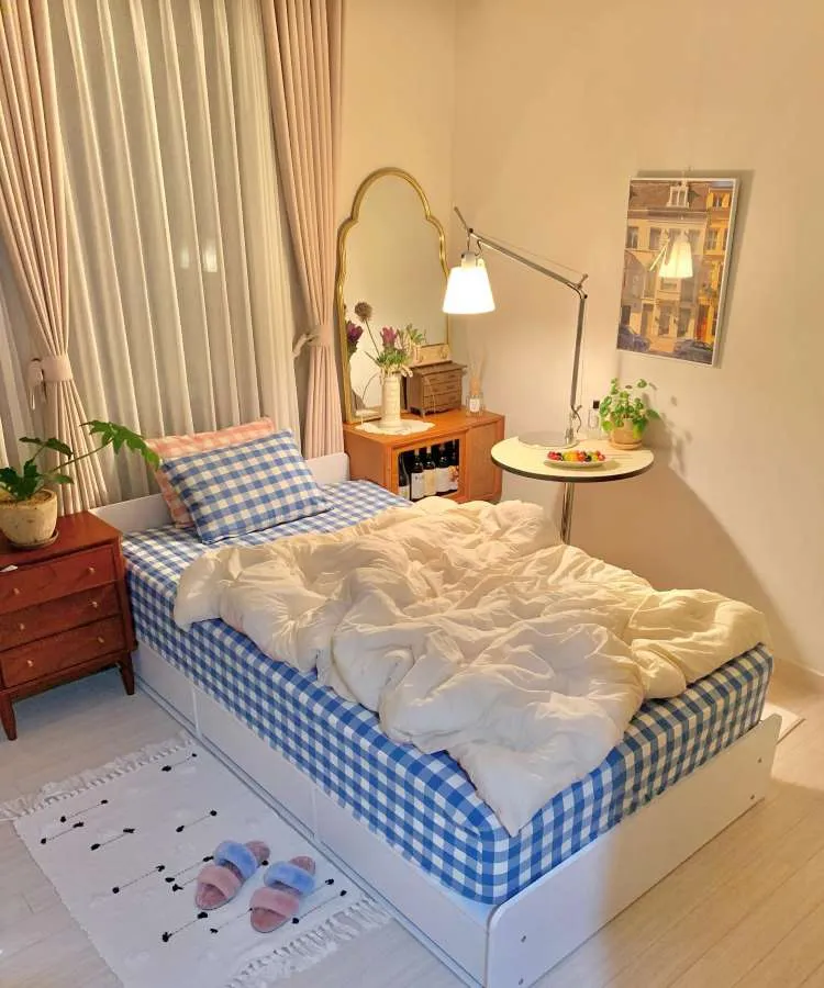 Quarto de solteiro com espelho, cores predominantes: azul, rosa, off-white, madeira