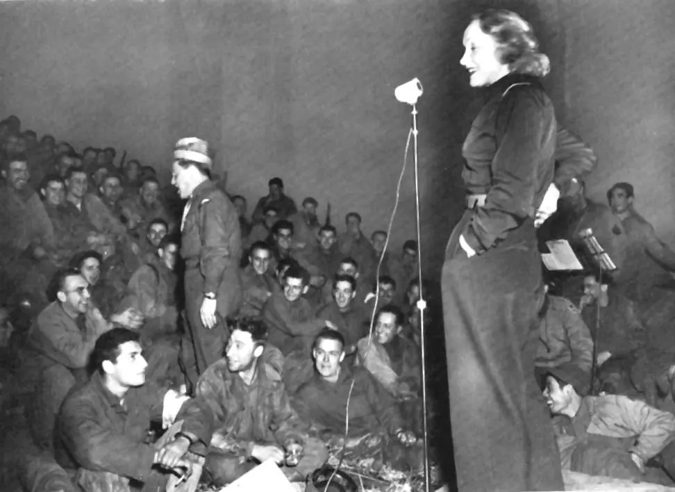 A atriz Marlene Dietrich a entreter soldados do exército, em 1944, vestida com calça e camisa. A Moda e Cidadania nos anos 40 e 50.