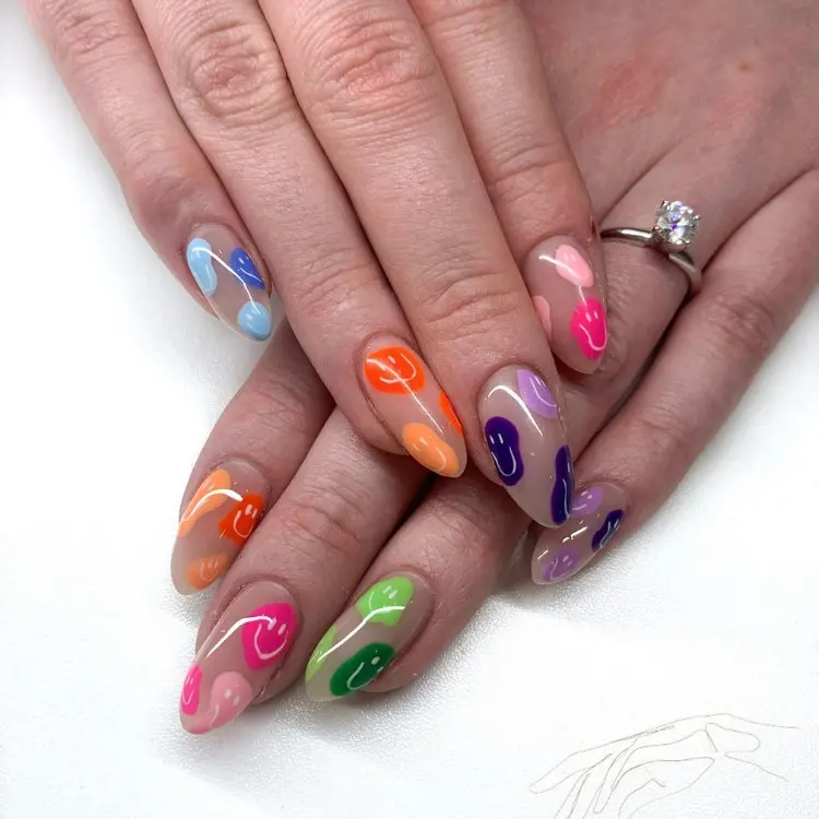 Unhas de fundo nude com carinhas derretidas nas cores do arco-íris
