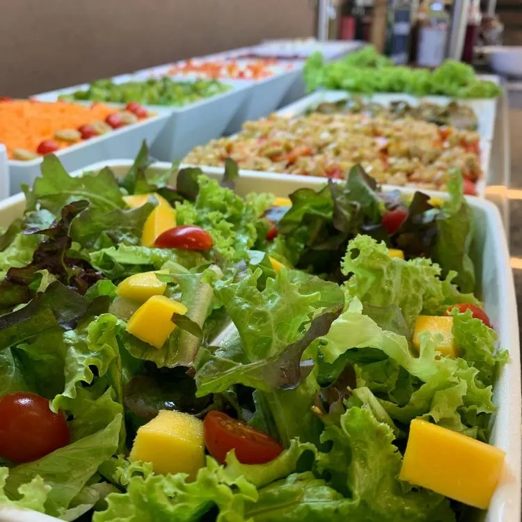 Uma mesa de saladas com uma salada de folhas em primeiro plano