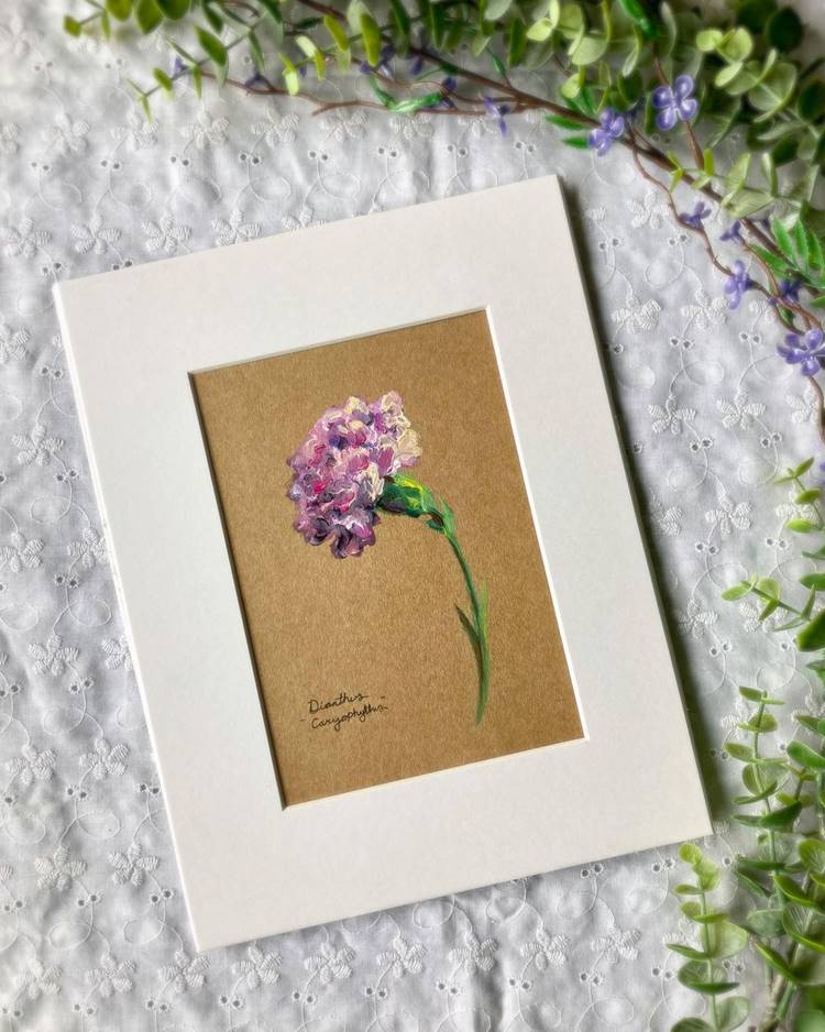 Pintura de flor emoldurada sob tecido branco ao lado de planta ariticial