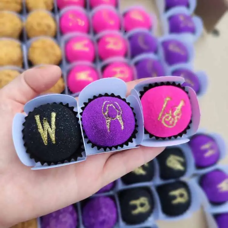doce de festa enrolado, preto, roxo e rosa com detalhes dourados de festa wandinha