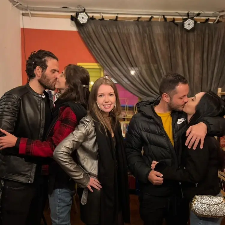 Dois casais heterossexuais se beijando e Raquel sozinha ao centro