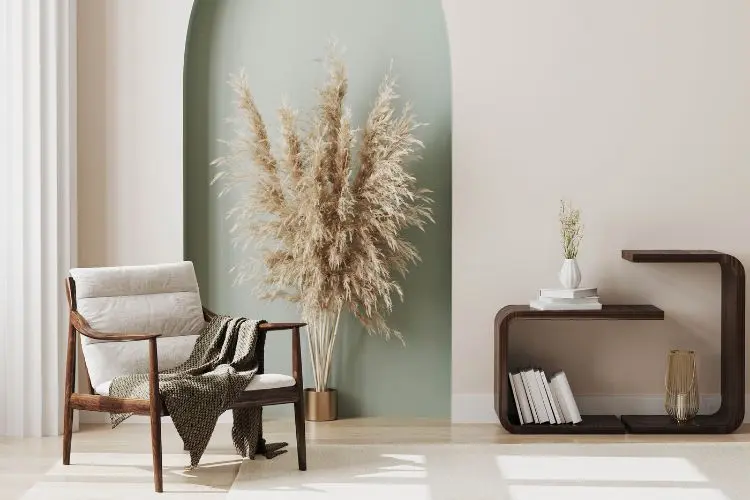 Espaço para relaxamento com planta bege, poltrona com manta e móvel  marrom com livros e vasos