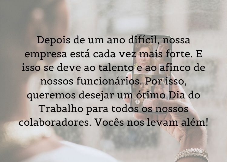Foto de pessoa segurando celular em ligação de vídeo com outras pessoas e frase "Depois de um ano difícil, nossa empresa está cada vez mais forte. E isso se deve ao talento e ao afinco de nossos funcionários. Por isso, queremos desejar um ótimo Dia do Trabalho para todos os nossos colaboradores. Vocês nos levam além!"