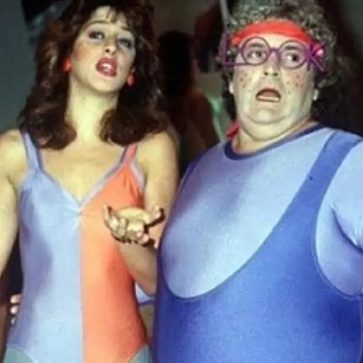 Claudia Raia de collant azul e laranja ao lado de Jô Soares de collant azul e faixa vermelha na cabeça