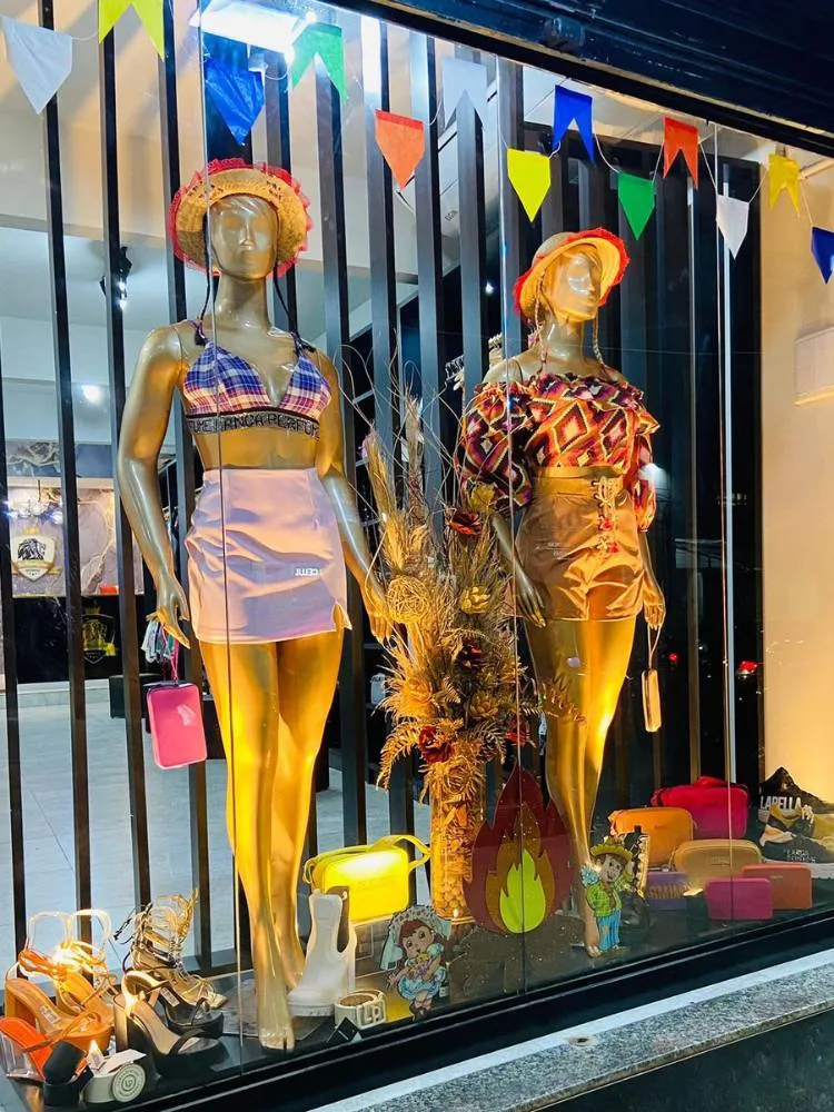 Vitrine de loja de roupas femininas com manequim usando roupa xadrez e chapéu de palha 