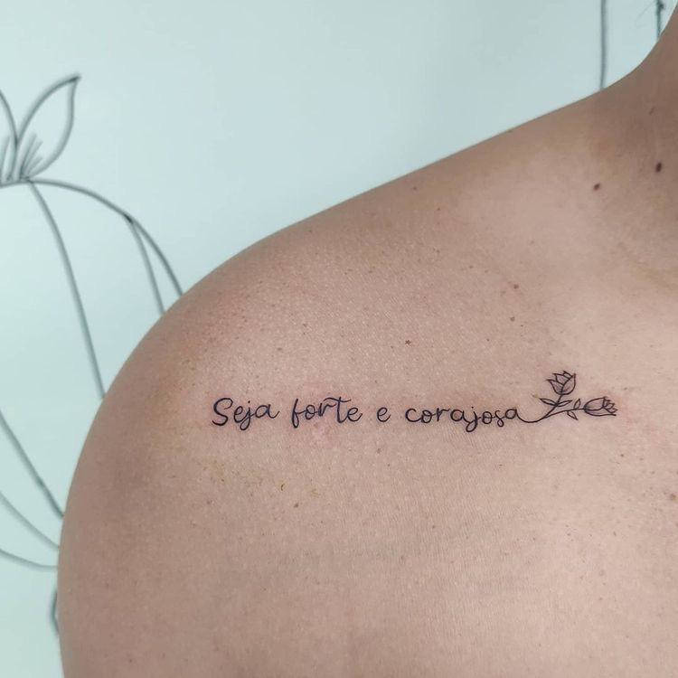 Tatuagem "seja forte e corajosa" no ombro com flores