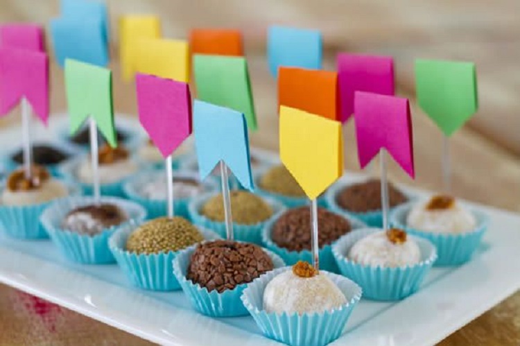 A imagem representa docinhos de festa junina decorados com tags de bandeirinha