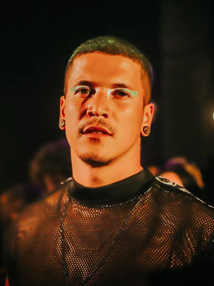 Homem com cabelo verde e make delineado gráfico nos olhos verde e branco