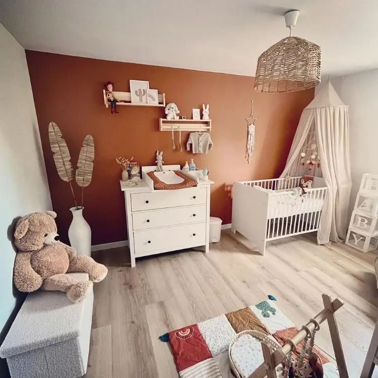 Quarto de bebê em bege e laranja queimado com brinquedos na decoração, como urso em banco baú e outros em prateleiras 