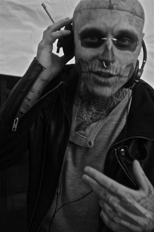 Homem com maquiagem de caveira, piercing e tatuagens 