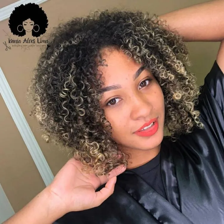 Mulher de pele morena com cabelo chanel crespo com luzes