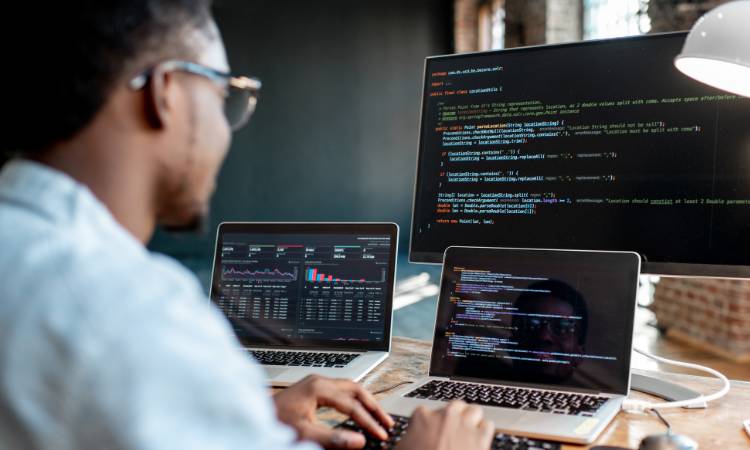Programador com três telas.