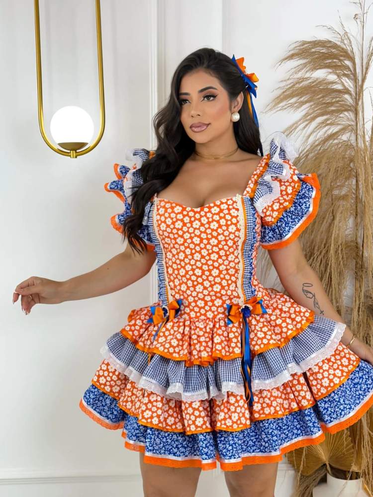 Mulher de pele clara maquiada, com vestido junino laranja e azul 