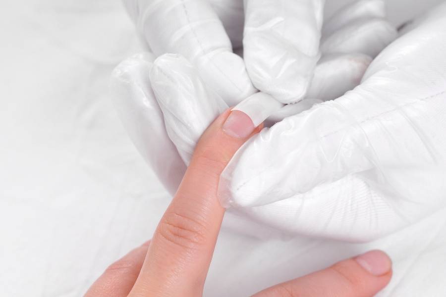 Profissional fazendo remoção de unhas postiças.