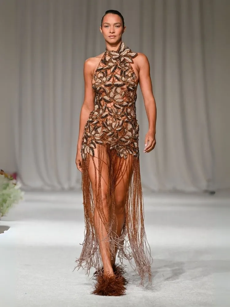 Foto de modelo desfilando com vestido de franjas da PatBo, uma das tendências da Semana de Moda de Nova York 2025