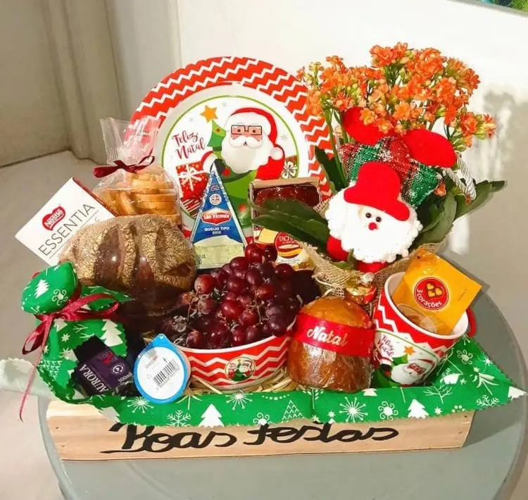 Cesta de Boas Festas em madeira com frutas, caneca, flores, pães e guloseimas