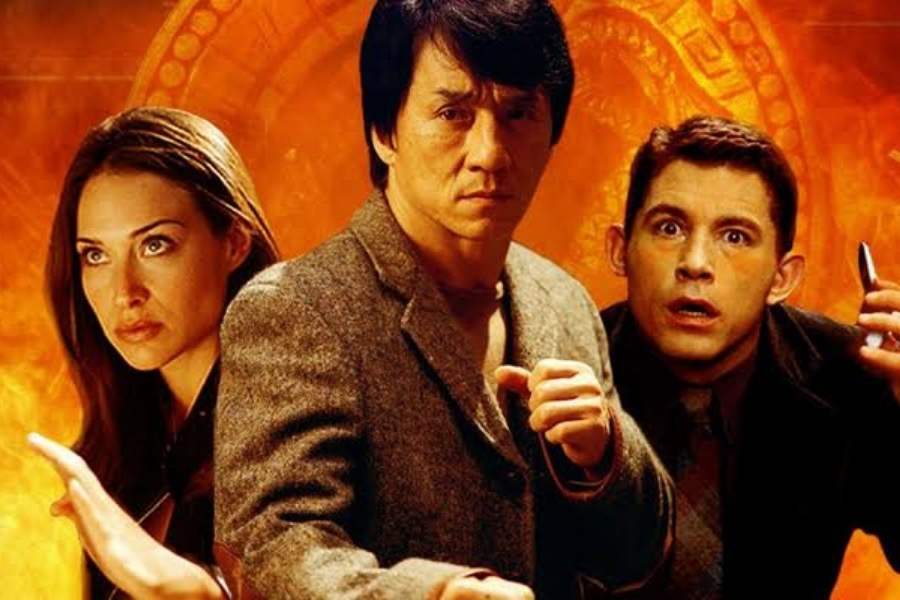 Foto de Eddie Yang (Jackie Chan), Nicole (Claire Forlani) e Arthur (Lee Evans). Os três estão um ao lado do outro, fazendo pose de luta. Ao fundo, tem foto do medalhão. Filme da Sessão da Tarde de 29 de agosto a 2 de setembro.