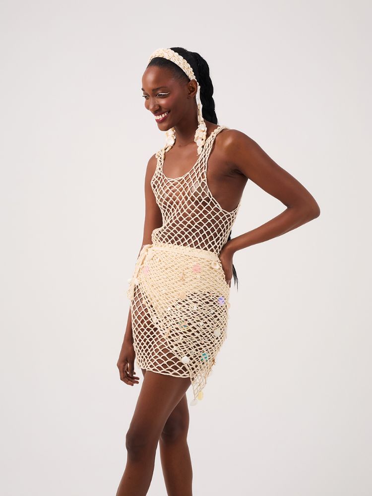 Mulher de pele negra usando vestido de crochê e hot pant bege 