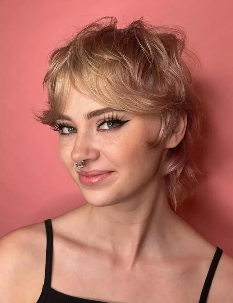 Menina com corte de cabelo curto bixie, usando piercing no nariz, maquiagem delineado e regata de alça fina preta