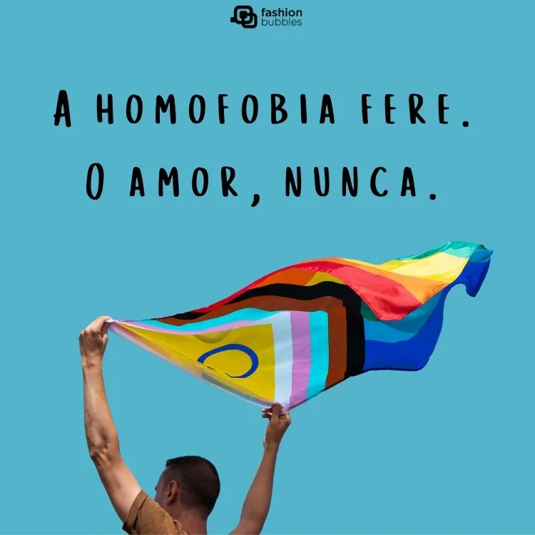 Foto de homem carregando a bandeira LGBTQIA+ com frase sobre homofobia