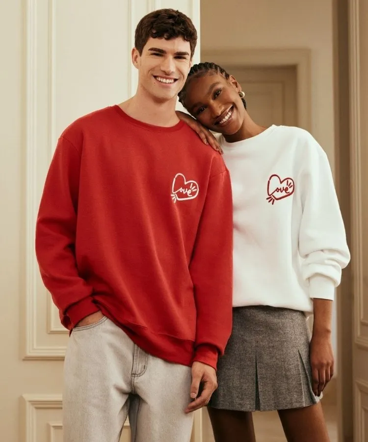 Foto de casal usando moletom vermelho e branco com bordado de coração