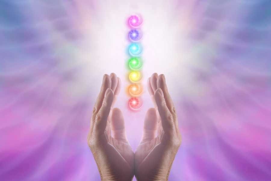Foto ilustrativa dos 7 chakras alinhados com mãos os segurando.