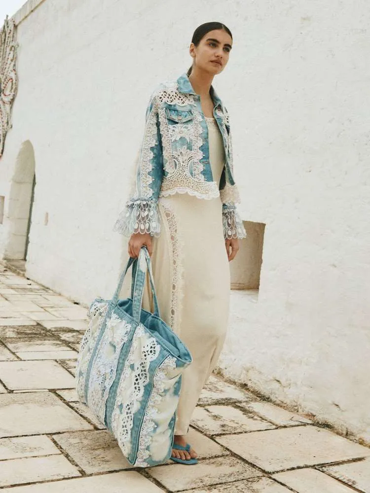 Mulher de pele clara usando vestido slip branco longo, jaqueta jeans com renda e bolsa jeans com renda 