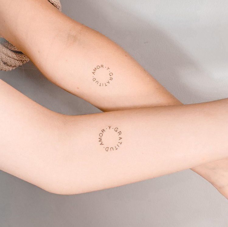 Tatuagem de frase "amor e gratidão" em espanhol em duas pessoas