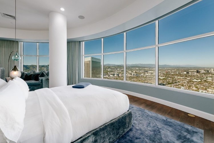 Quarto da mansão da Rihanna, com cama, estofado e vista para a cidade.