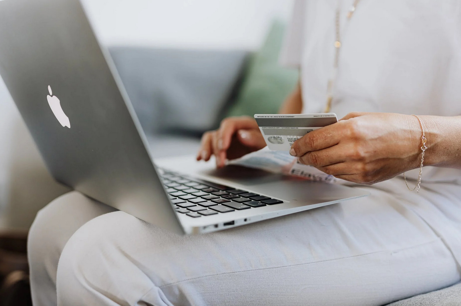 Mulher com laptop no colo e cartão de crédito na mão Como montar uma loja virtual de semijoias