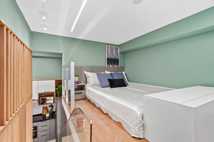 Dormitório com parede verde, cama de casal, teto branco, piso de madeira