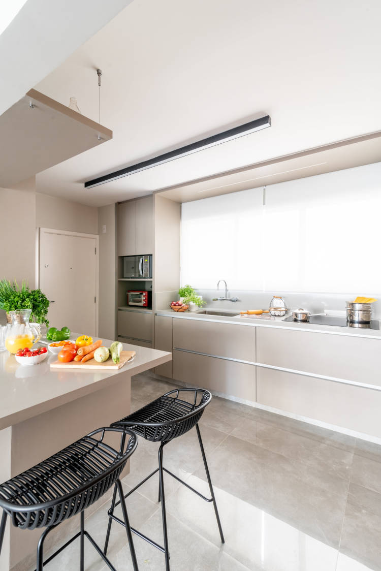 Apartamento decorado antes e depois com ilha, bancadas altas e revestimentos modernos.