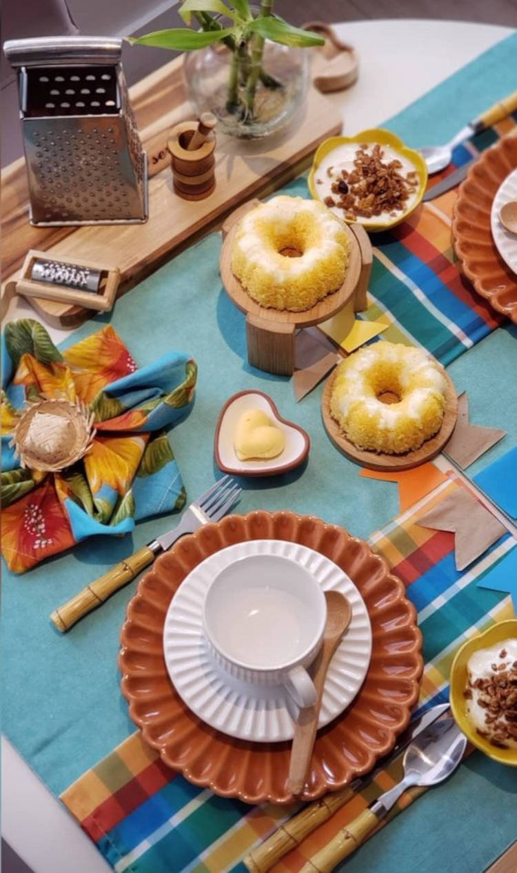 A imagem representa decoração para festa junina. Contém bolo, canjica, em mesa para dois, com guardanapos xadrezes
